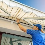 worker install an awning on the house wall over the terrace window